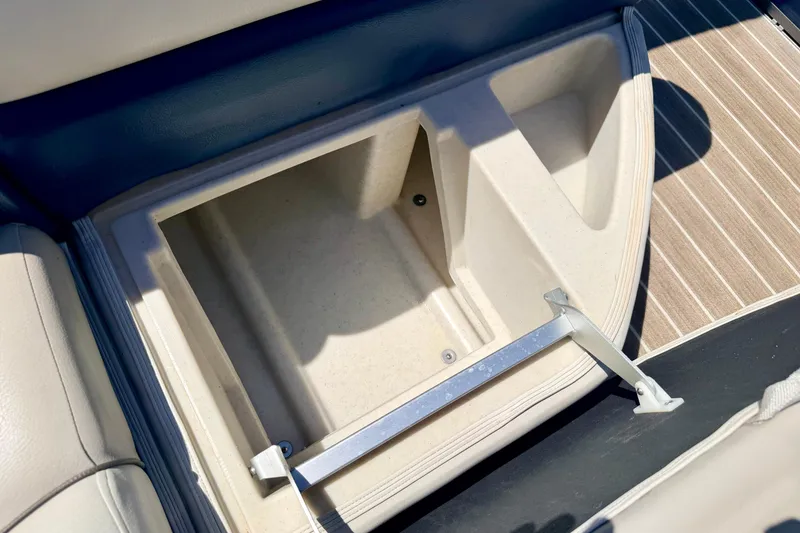 Slide: The Image of Storage compartment on a 2015 Manitou 25 SES BENCH boat, featuring beige interior and striped flooring. - 61