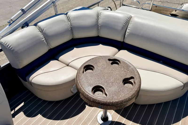 Slide: The Image of 2015 Manitou 25 SES BENCH boat interior with cushioned seating and round table. - 54