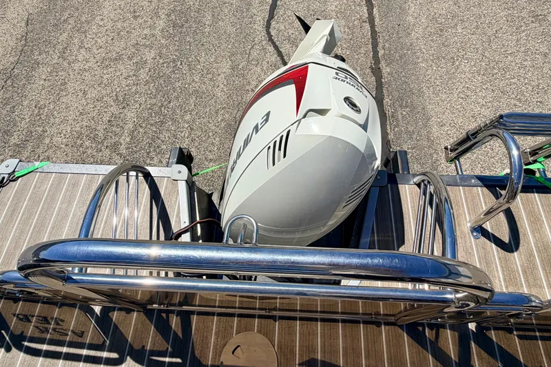 Slide: The Image of 2015 Manitou 25 SES BENCH boat with Evinrude outboard motor on wooden deck. - 74