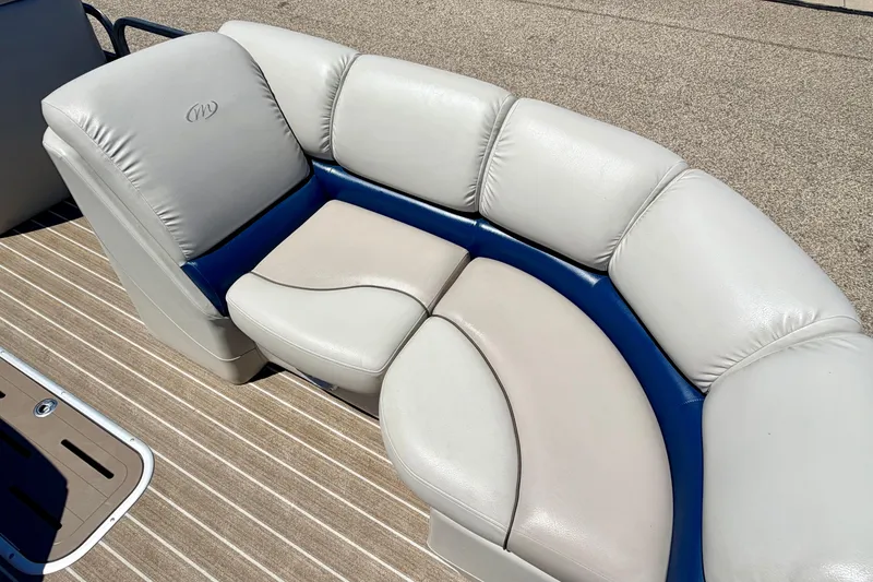 Slide: The Image of Luxurious seating on 2015 Manitou 25 SES BENCH pontoon boat, featuring plush white and blue upholstery. - 39