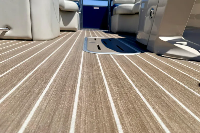 Slide: The Image of 2015 Manitou 25 SES BENCH boat interior with striped flooring and cushioned seating. - 89