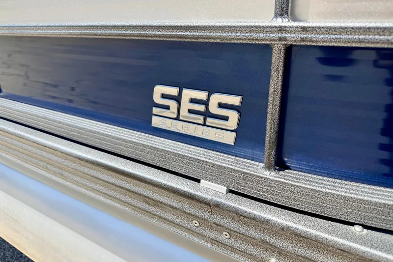 Slide: The Image of 2015 Manitou 25 SES BENCH boat with SES Series emblem on blue panel. - 5