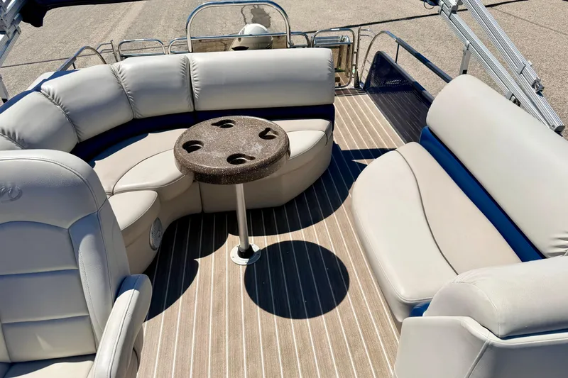 Slide: The Image of 2015 Manitou 25 SES BENCH boat interior with cushioned seating and round table. - 67