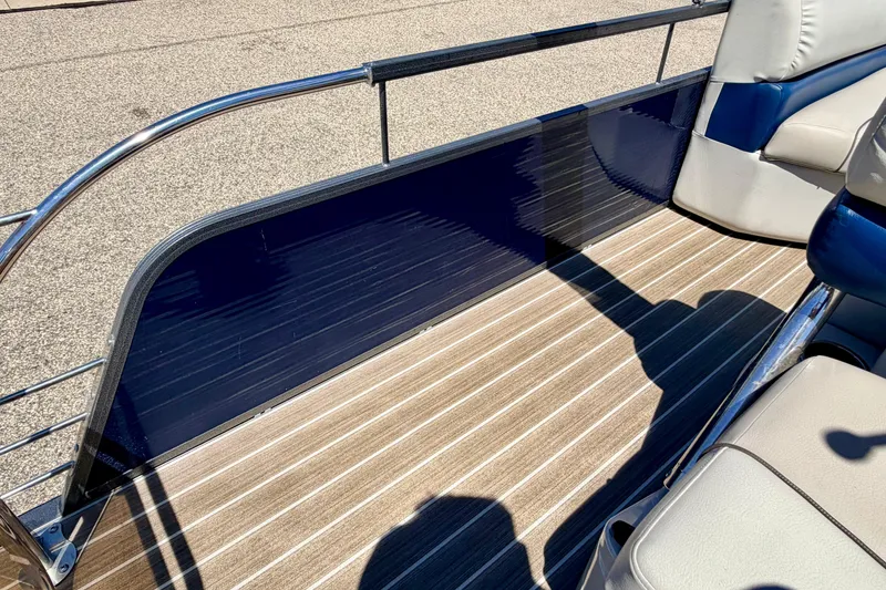 Slide: The Image of 2015 Manitou 25 SES BENCH boat interior with striped flooring and cushioned seating. - 77