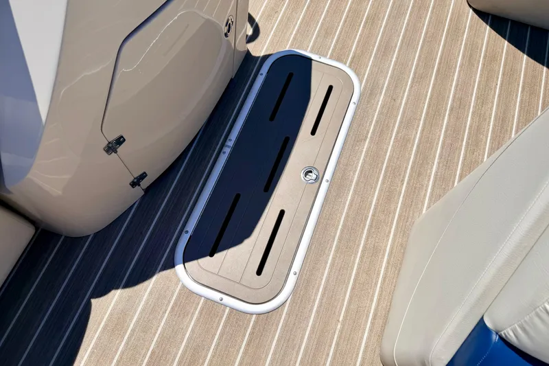 Slide: The Image of 2015 Manitou 25 SES BENCH boat interior with striped flooring and storage compartment. - 40