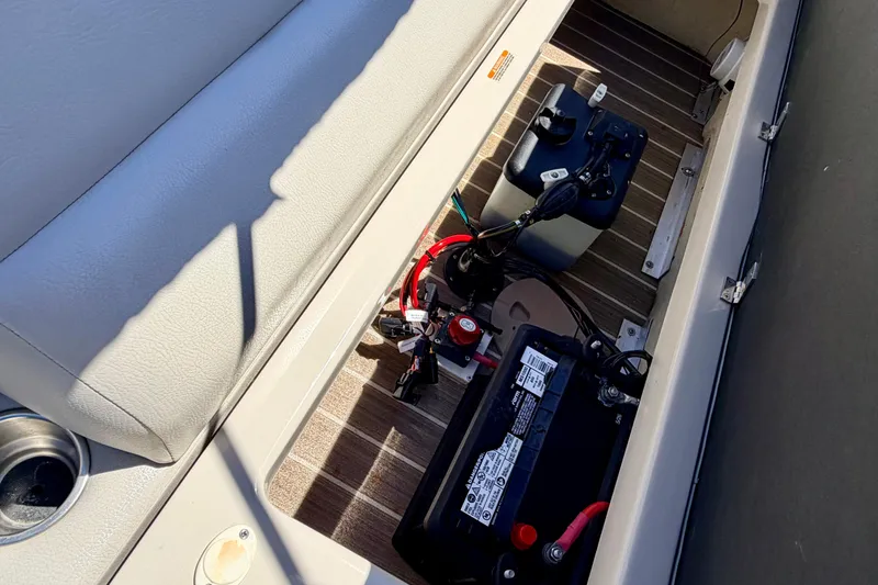 Slide: The Image of 2015 Manitou 25 SES BENCH boat storage compartment with battery and wiring. - 71