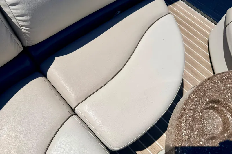 Slide: The Image of 2015 Manitou 25 SES BENCH boat seating with beige upholstery and wooden flooring. - 60