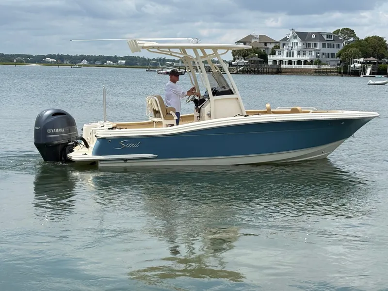 Slide: The Image of A 2019 Scout 215 XSF boat on calm water with houses in the background. - 9