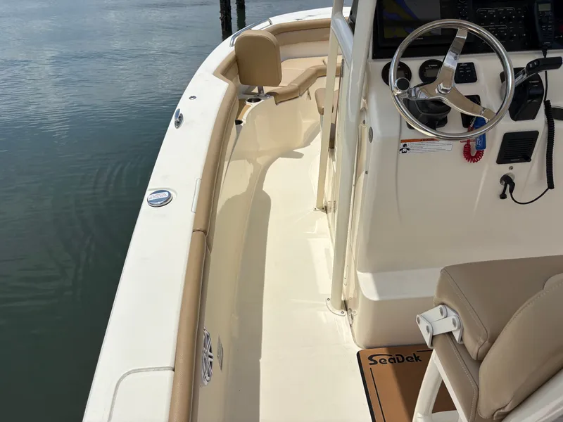 Slide: The Image of The image shows the deck of a 2019 Scout 215 XSF boat with beige seating and a helm. - 20