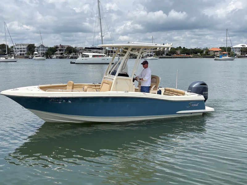 Slide: The Image of A 2019 Scout 215 XSF boat on calm water with a person on board. - 2