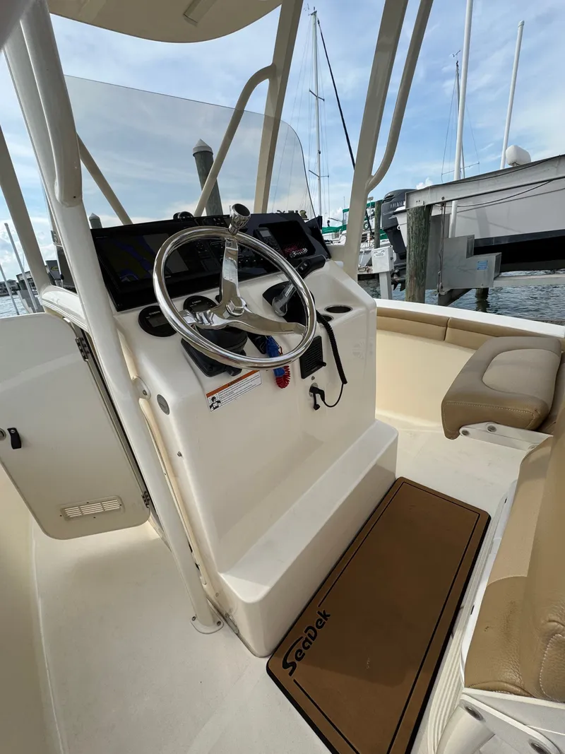 Slide: The Image of The image shows the cockpit of a 2019 Scout 215 XSF boat with a helm and beige seating. - 42