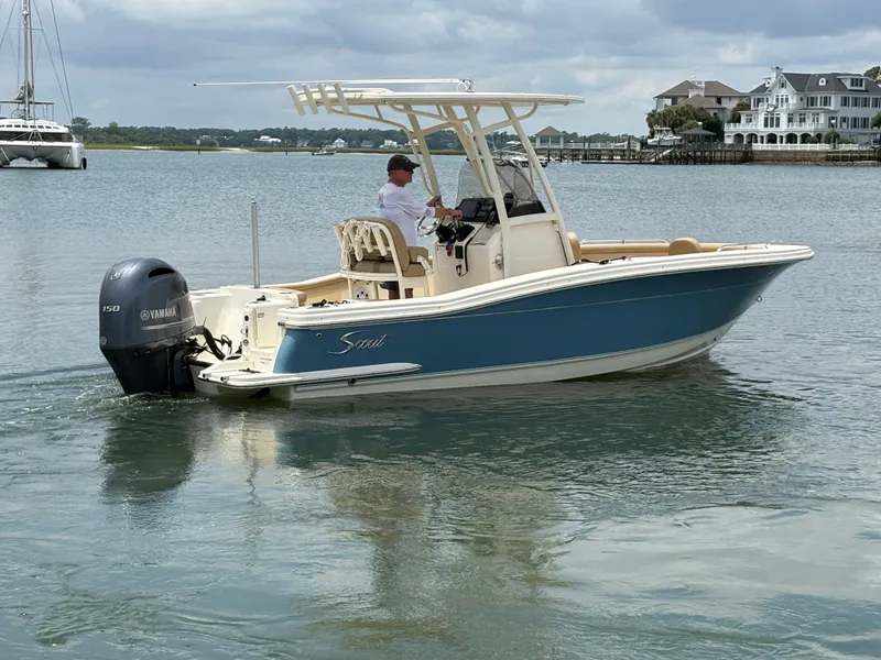 Slide: The Image of A 2019 Scout 215 XSF boat on calm water. It features a blue hull and a T-top. - 8