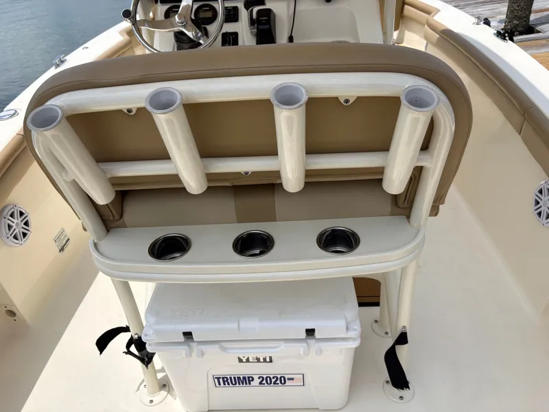 Slide: The Image of The image shows the cockpit of a 2019 Scout 215 XSF boat. There's a beige bench seat with integrated rod holders and a Yeti cooler underneath. - 47