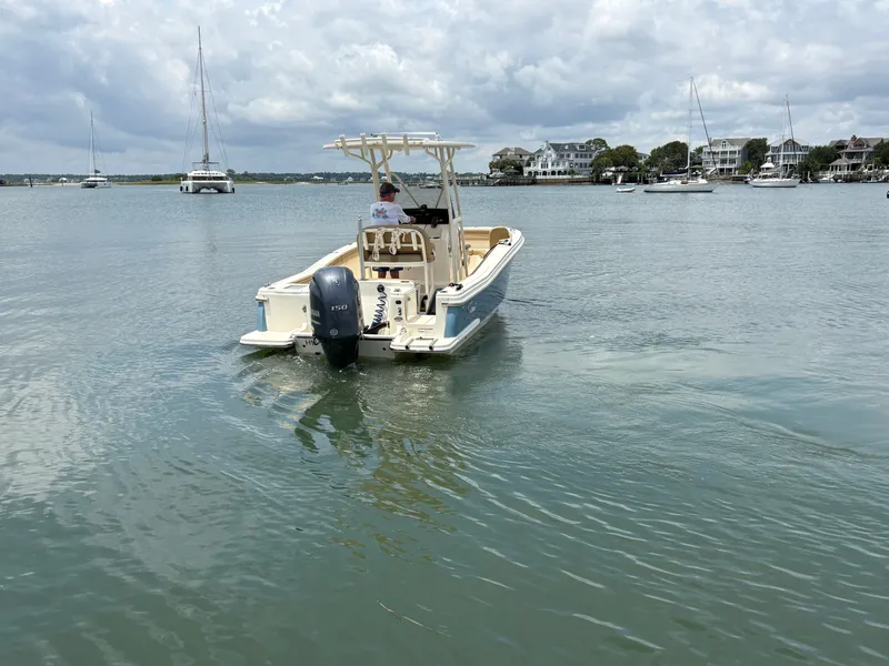 Slide: The Image of A 2019 Scout 215 XSF boat on calm water. Sailboats and houses are visible in the background. - 6