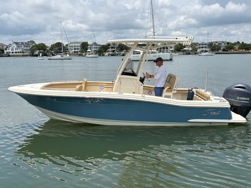 Slide: The Image of A 2019 Scout 215 XSF boat on calm water with a man at the helm. - 1