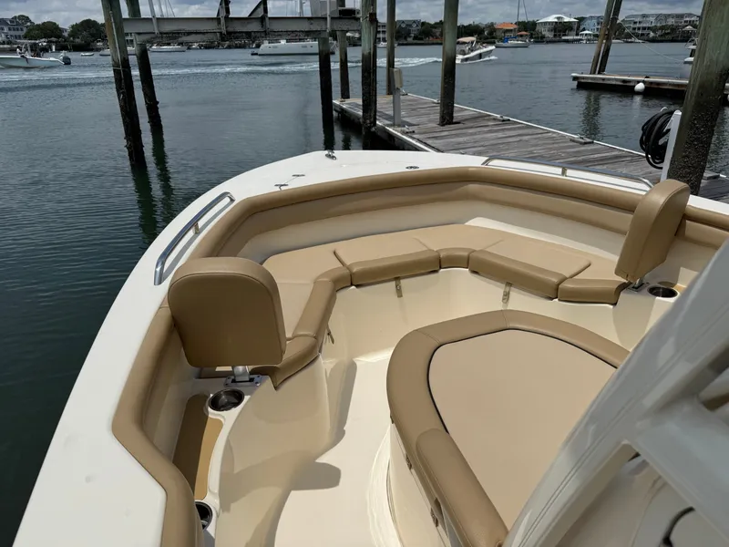 Slide: The Image of A 2019 Scout 215 XSF boat with beige upholstery in the bow area, docked at a calm harbor. - 27