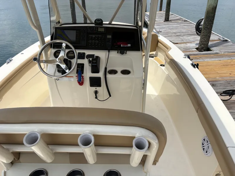 Slide: The Image of The image shows the cockpit of a 2019 Scout 215 XSF boat. It features a modern helm and rod holders. - 17