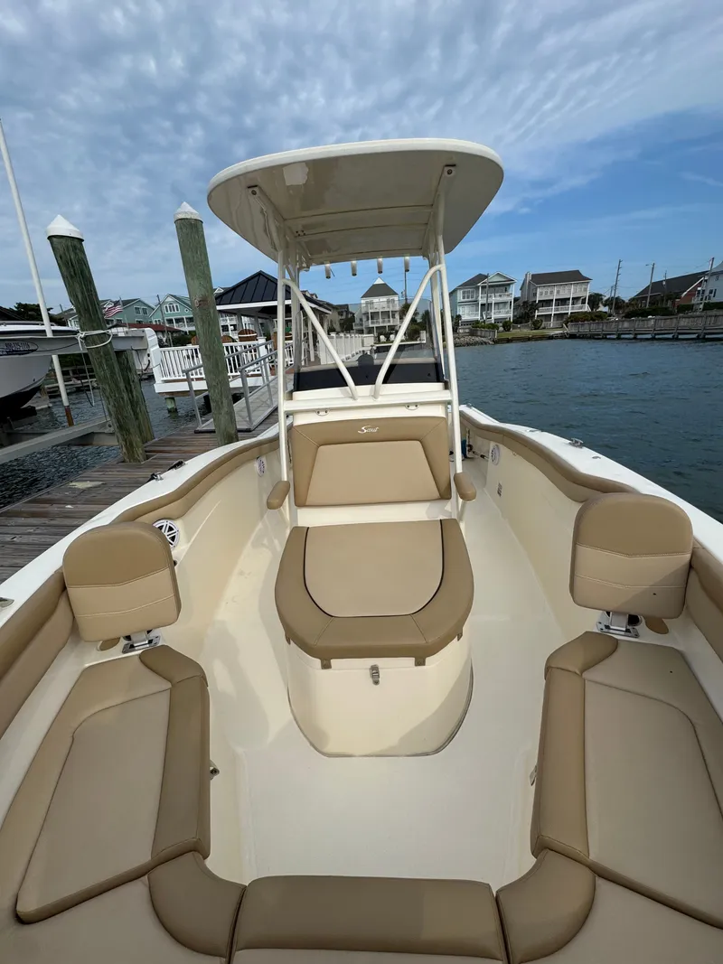 Slide: The Image of A 2019 Scout 215 XSF boat docked. It features beige upholstery and a T-top. - 24