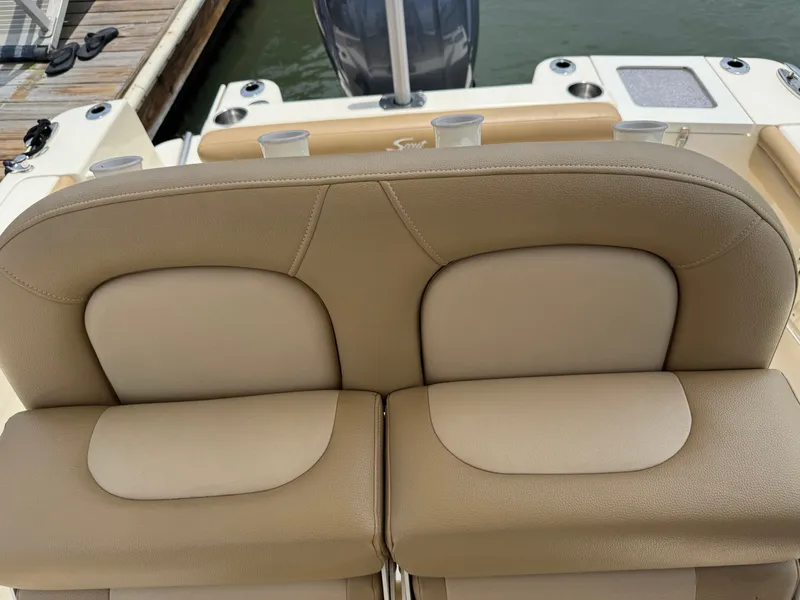 Slide: The Image of Rear view of a beige boat seat on a Scout 215 XSF, overlooking the water. - 43