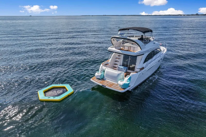Slide: The Image of A 2004 Meridian 411 Sedan yacht on calm waters with a floating trampoline nearby. - 6