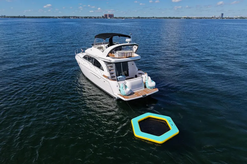 Slide: The Image of 2004 Meridian 411 Sedan yacht anchored with floating platform on calm blue water. - 5