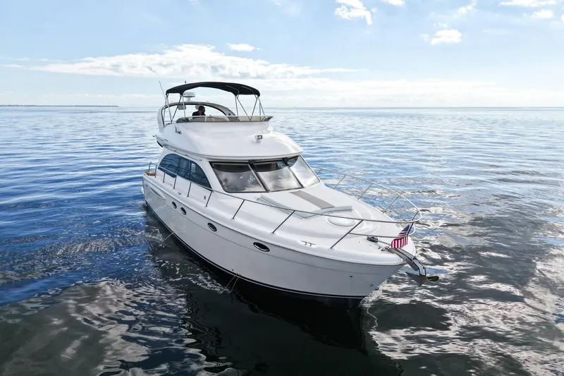 Slide: The Image of 2004 Meridian 411 Sedan yacht cruising on calm ocean waters under a clear sky. - 2
