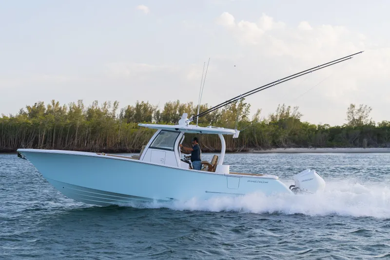 Slide: The Image of 2026 Phenom 34 Center Console boat cruising on water near a forested shoreline. - 2