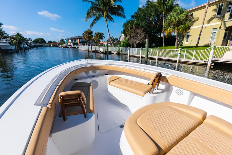 Slide: The Image of 2026 Phenom 34 Center Console boat with tan seating, docked by a waterfront home. - 24