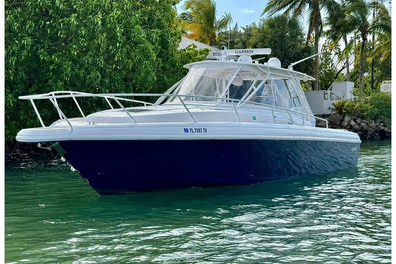 The Image of 2006 Intrepid 377 Walkaround boat on water, surrounded by lush greenery and palm trees. - 0