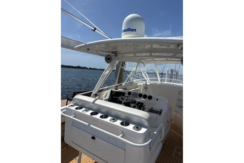 Slide: The Image of 2006 Intrepid 377 Walkaround boat cockpit with navigation equipment and seating, on calm water. - 12