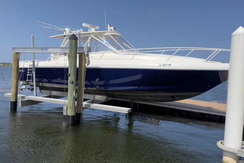 Slide: The Image of 2006 Intrepid 377 Walkaround boat on lift at dockside, blue and white exterior. - 5