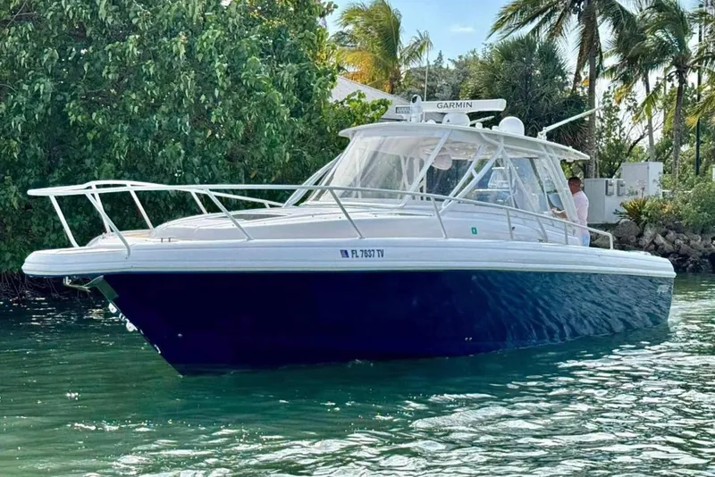 The Image of 2006 Intrepid 377 Walkaround boat on water, surrounded by lush greenery and palm trees. - 1