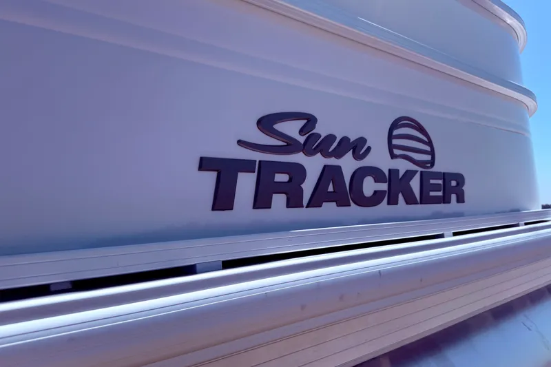 Slide: The Image of 2026 Sun Tracker Party Barge 24 XP3 logo on boat exterior in sunlight. - 13