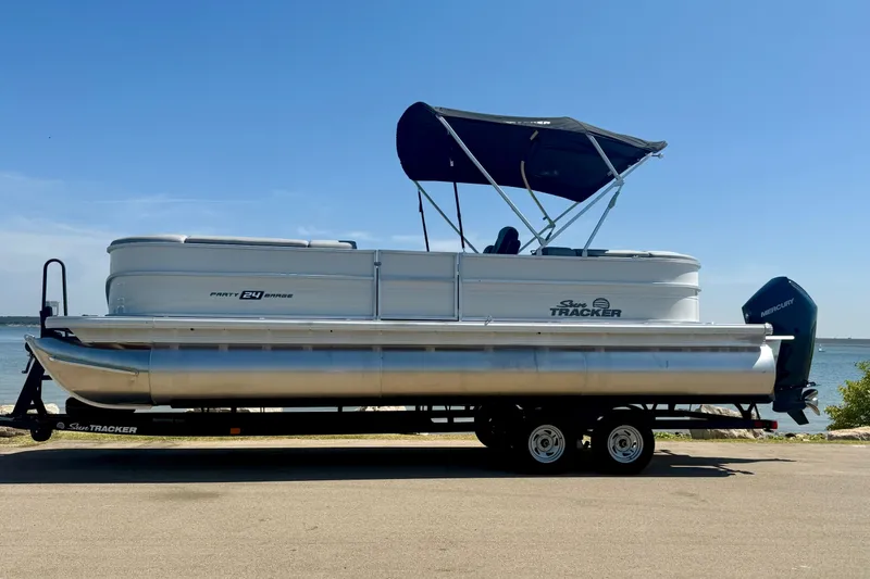 Slide: The Image of 2026 Sun Tracker Party Barge 24 XP3 pontoon boat on trailer by the water. - 11