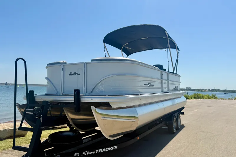 Slide: The Image of 2026 Sun Tracker Party Barge 24 XP3 pontoon boat on trailer by the water. - 10