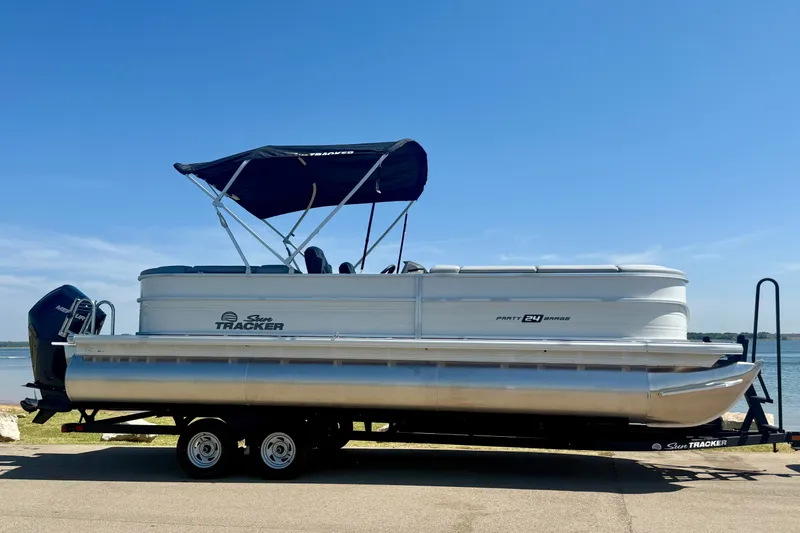 Slide: The Image of 2026 Sun Tracker Party Barge 24 XP3 pontoon boat on trailer by the water. - 2