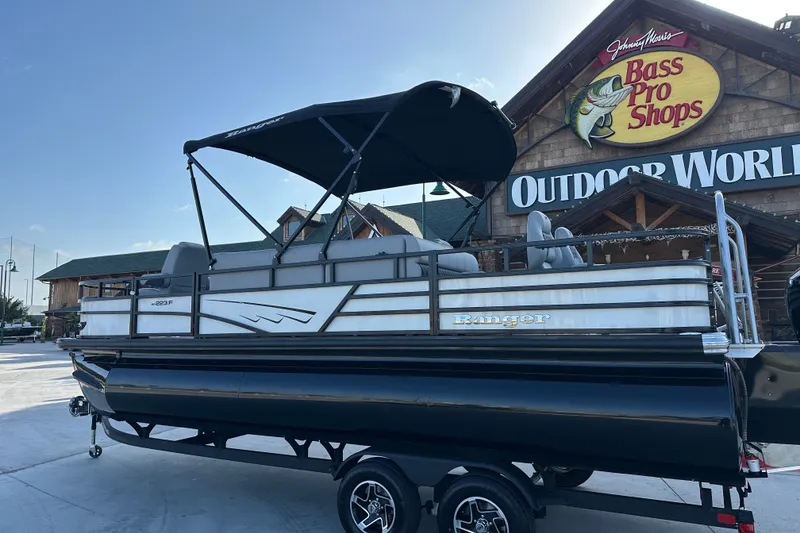 Slide: The Image of 2026 Ranger 223F pontoon boat displayed outside Bass Pro Shops Outdoor World. - 87