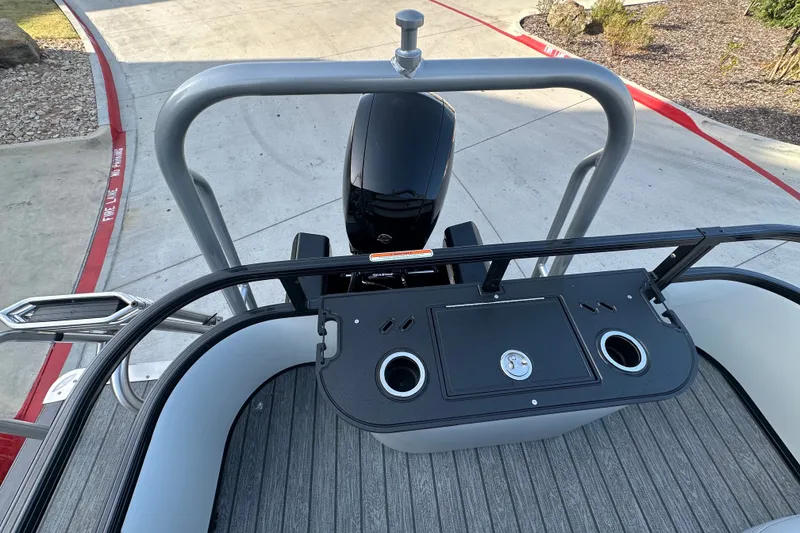 Slide: The Image of 2026 Ranger 223F boat deck with motor and cup holders, parked on concrete. - 80