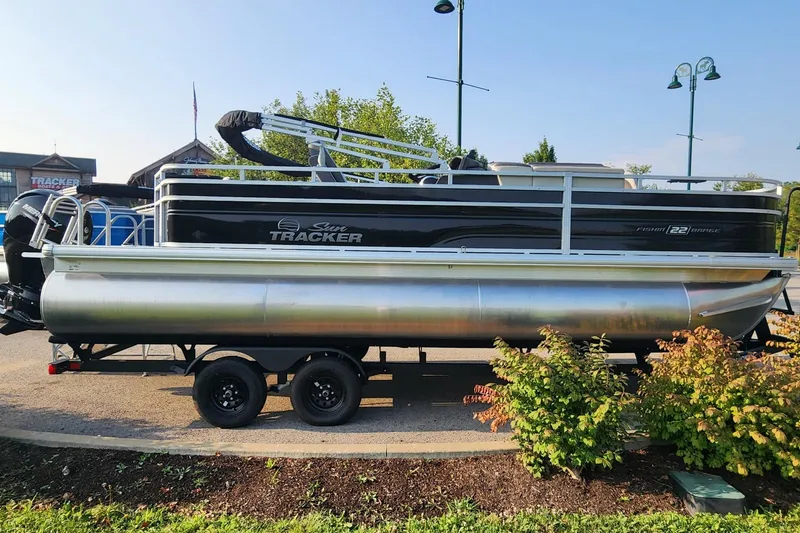 The Image of 2026 Sun Tracker Fishin' Barge 22 XP3 pontoon boat on trailer, parked outdoors. - 0
