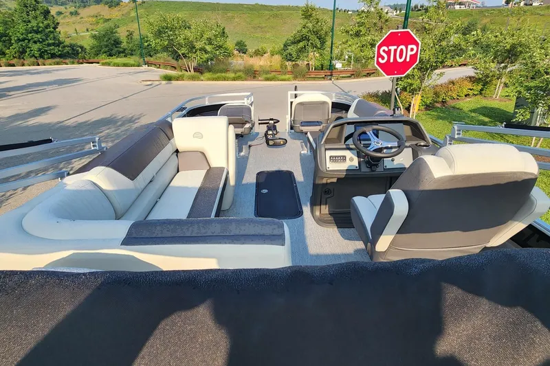 Slide: The Image of 2026 Sun Tracker Fishin' Barge 22 XP3 interior with seating and steering wheel, parked near stop sign. - 4