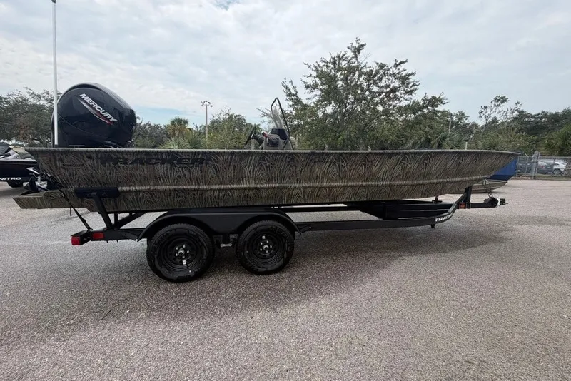 The Image of 2026 Tracker Grizzly 2072 CC boat on trailer, featuring camouflage design and Mercury outboard motor. - 0