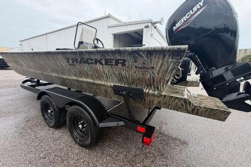 Slide: The Image of 2026 Tracker Grizzly 2072 CC boat with camo design on a trailer, featuring a Mercury outboard motor. - 3