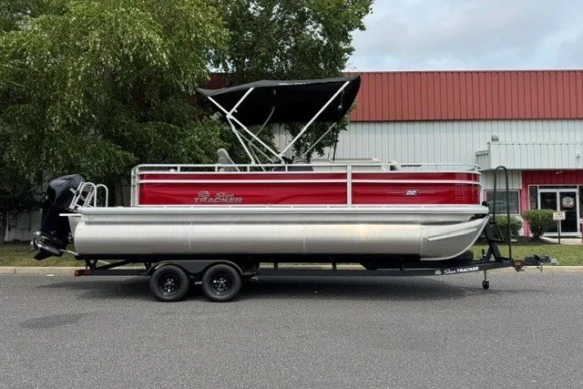 The Image of 2026 Sun Tracker Fishin' Barge 22 XP3 pontoon boat on trailer, parked outdoors. - 0