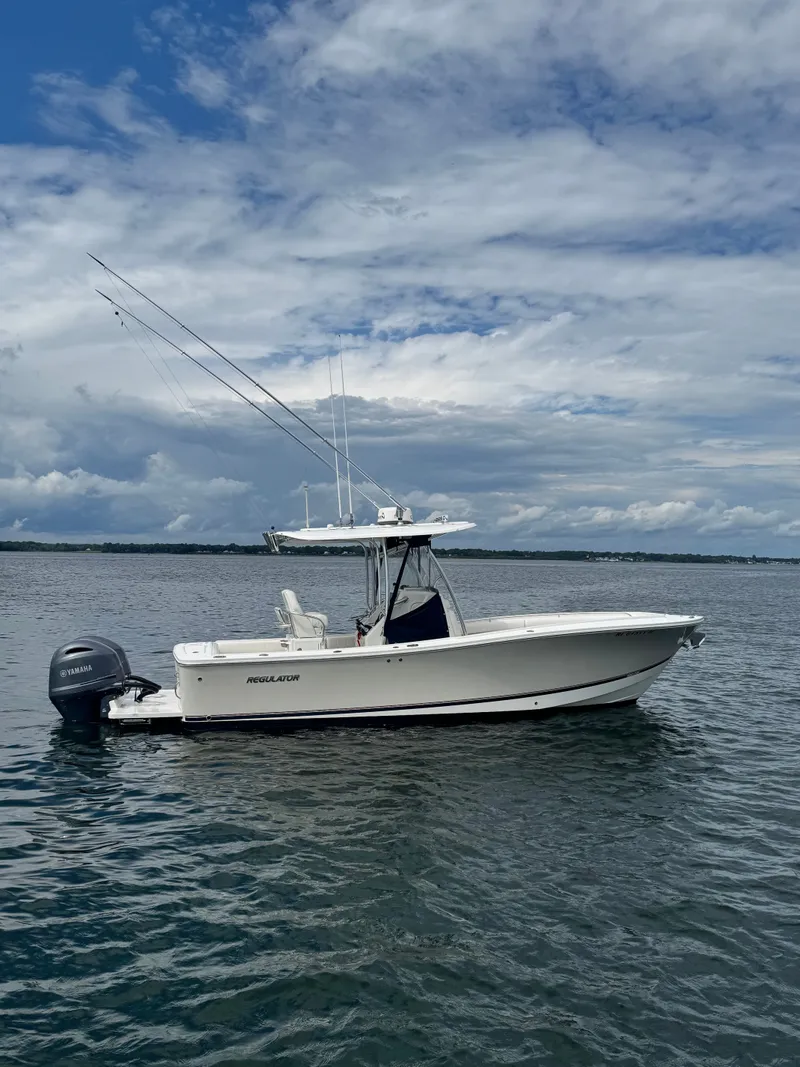 Slide: The Image of A white 2015 Regulator 25 boat floats on calm water under a cloudy sky. - 3