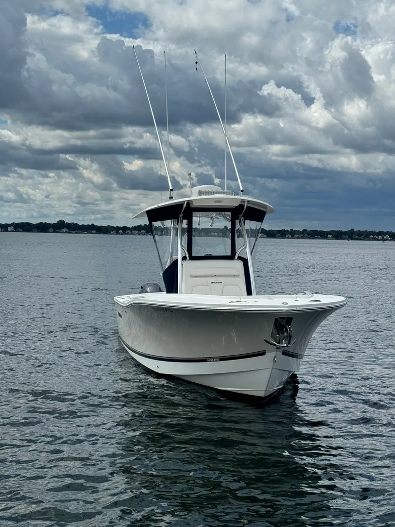 Slide: The Image of A white 2015 Regulator 25 boat floats on calm water under a cloudy sky. - 6