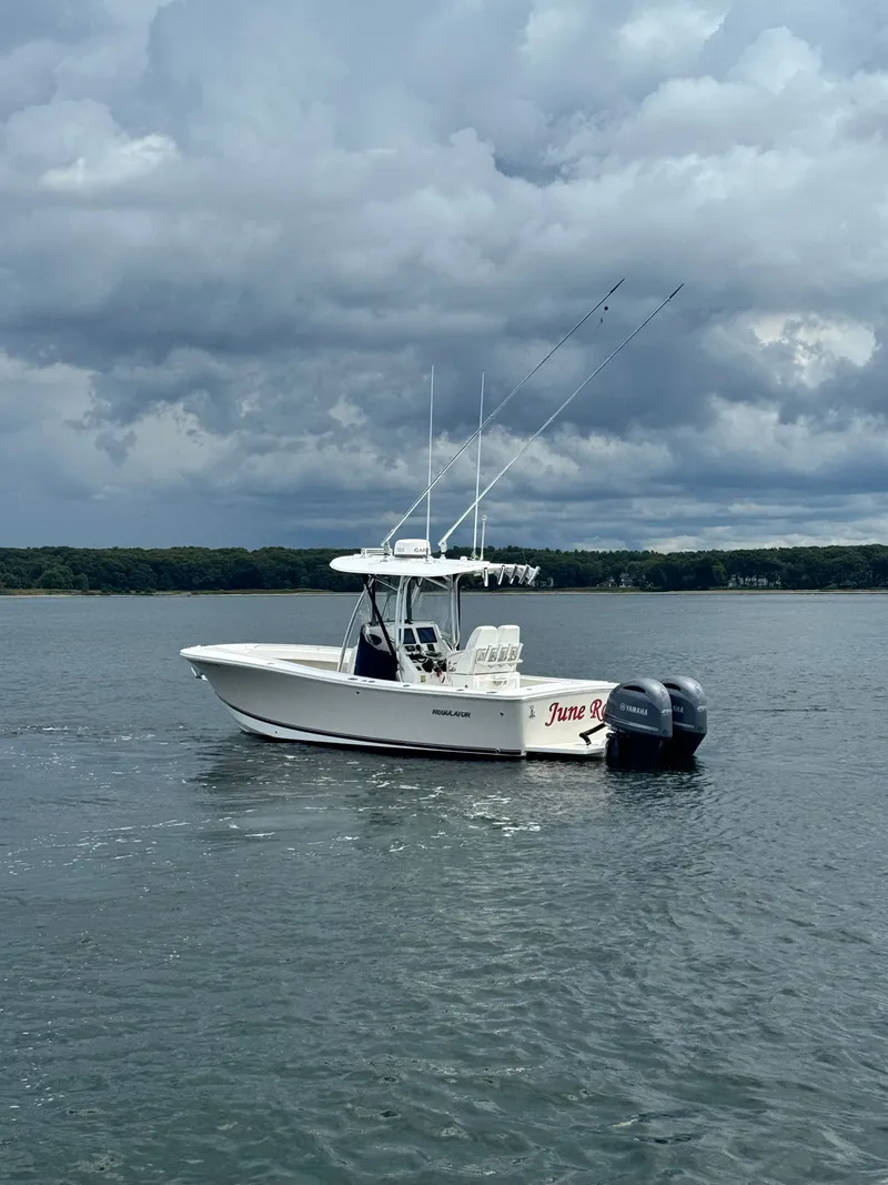 Slide: The Image of A 2015 Regulator 25 boat on calm water with twin outboard engines and fishing rods. - 7