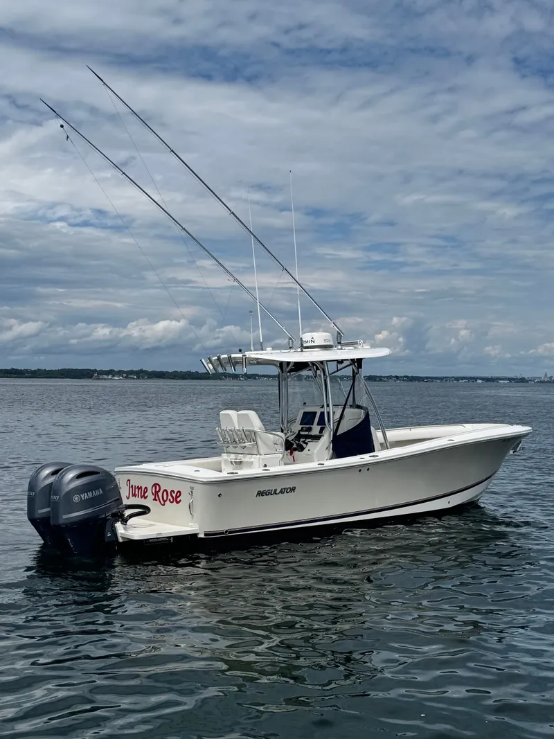 Slide: The Image of A 2015 Regulator 25 boat on calm water. It features twin outboard engines and fishing rods. - 2