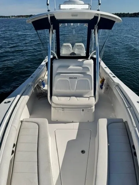 Slide: The Image of A 2015 Regulator 25 boat on the water. It features white upholstery and a T-top. - 10