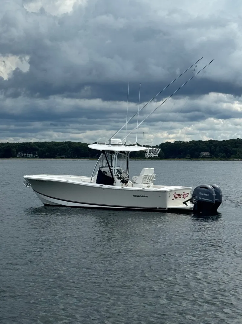 Slide: The Image of A 2015 Regulator 25 boat floats on calm water under a cloudy sky. - 4