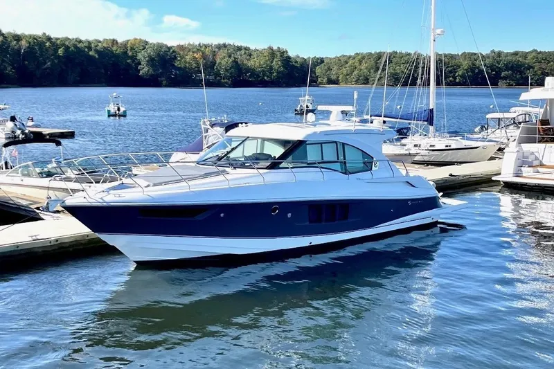 Slide: The Image of 2018 Cruisers Yachts 45 Cantius docked on a serene lake under a clear sky. - 2